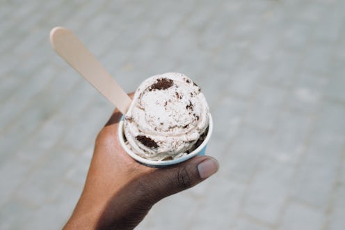 Personal perspective of unrecognizable black woman holding a cup of cookies and cream ice cream on a...