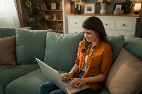 Young woman working on her laptop in comfort of her home.