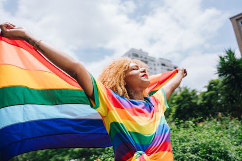 Transgender female holding a rainbow flag outdoors