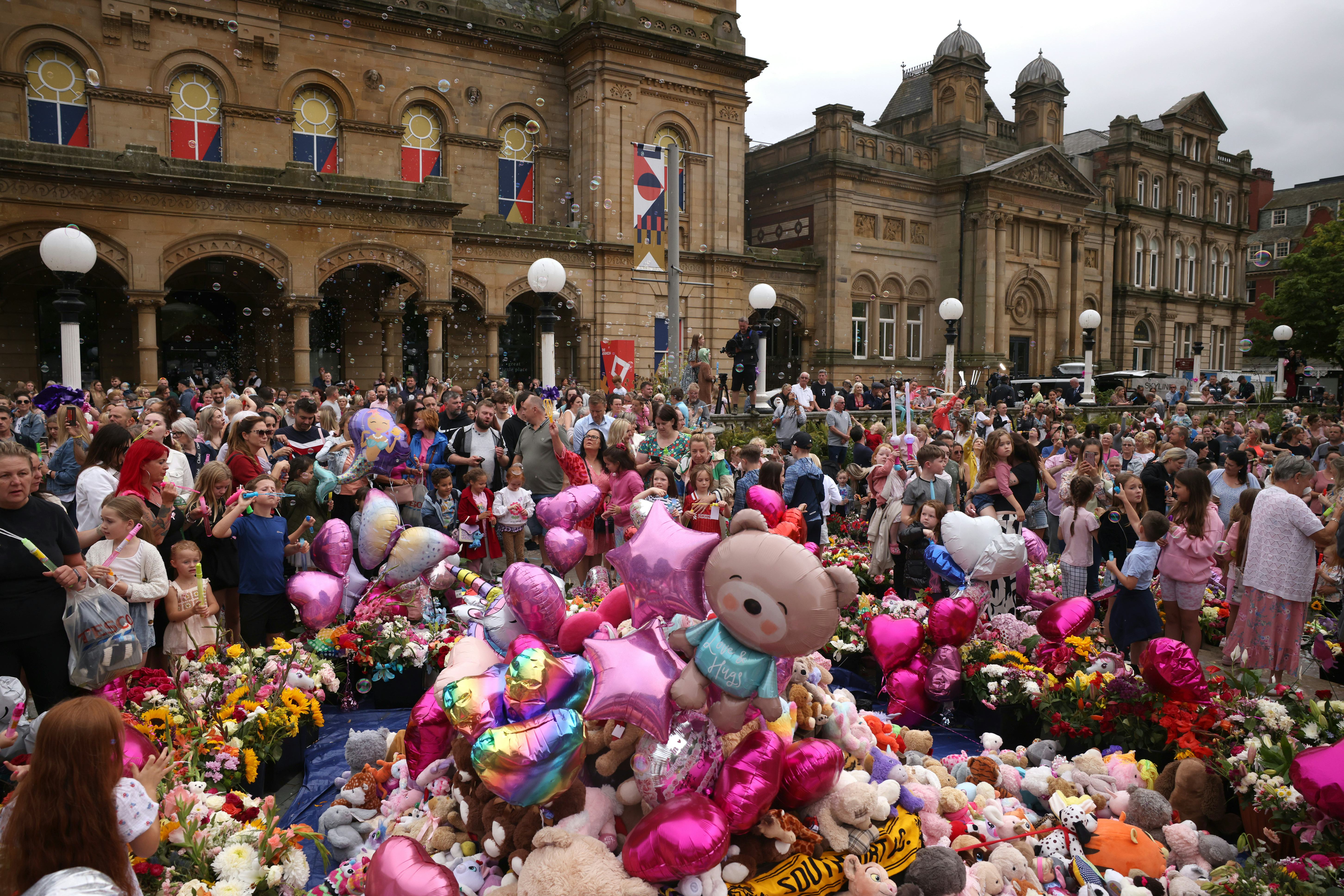 Adults and children mourn victims of the Southport attack by holding a vigil