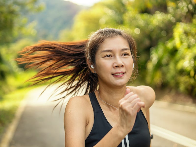 headshot of athlete woman jogging outdoor on country road in morning