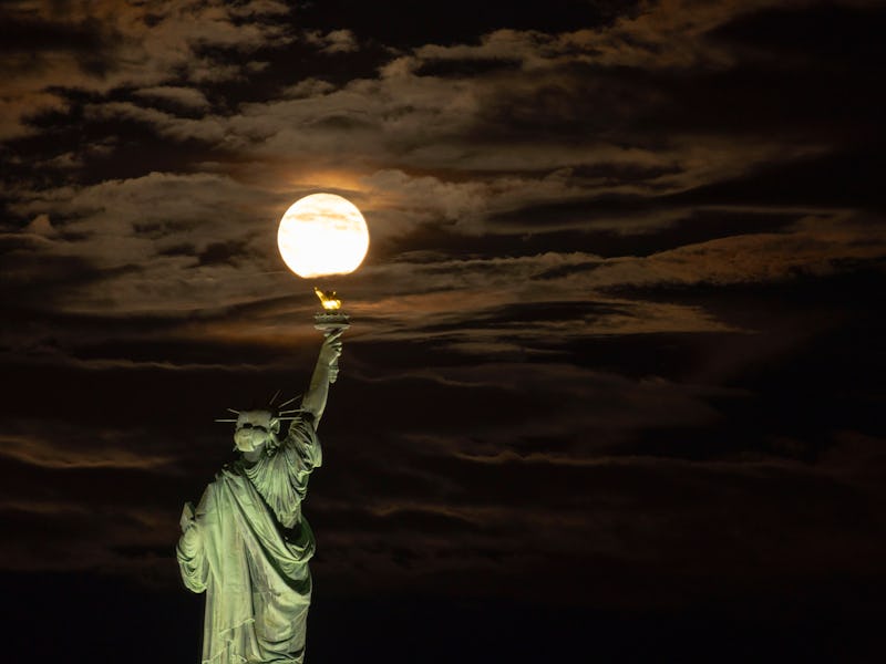 JERSEY CITY, NJ - AUGUST 19: The Blue Sturgeon Supermoon rises out of clouds behind the Statue of Li...