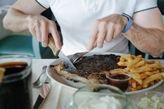 Man eating a half rack of ribs with side of fries at restaurant. A Redditor wants to know "AITAH" fo...