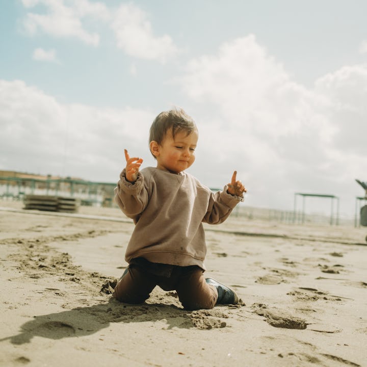 A baby boy is playing on the beach. He's having fun at the beach. Spring day.