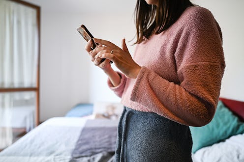 side view portrait of unrecognizable woman using telephone in a bedroom.