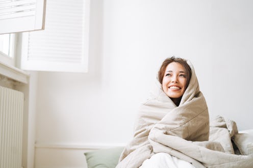 Young asian woman in blanket woke up in bed at home