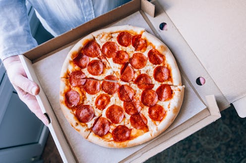 A man holding a pizza box. Close-up.