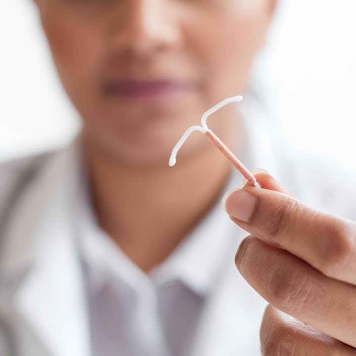 A doctor is holding an IUD (intrauterine device). The CDC recently updated it's recommendations for ...
