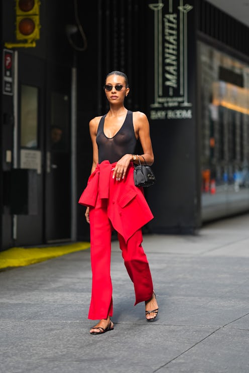 NEW YORK, NEW YORK - SEPTEMBER 09: A guest wears black sunglasses, black sheer mesh halter top, brig...