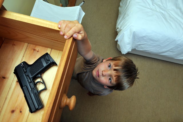Boy reaching up to a bedroom drawer that contains a gun. Securely storing guns has been found to dec...
