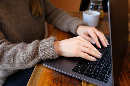 Women's hands type text on the keyboard of a computer or laptop. An office worker at his desk, in a ...