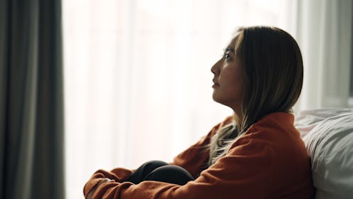 Woman depression hugging herself in bedroom.