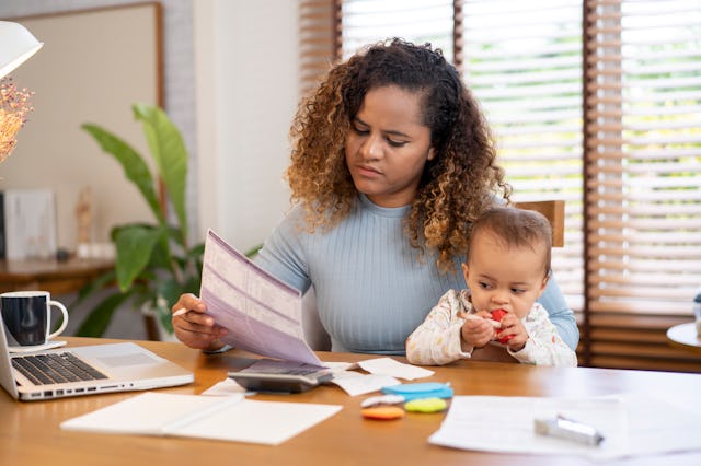 Mother and her baby sitting at the table with a laptop. Moms tend to go back to work earlier than re...