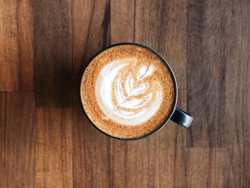 Cappuccino with cinnamon and latte art on the wooden table View from above.
