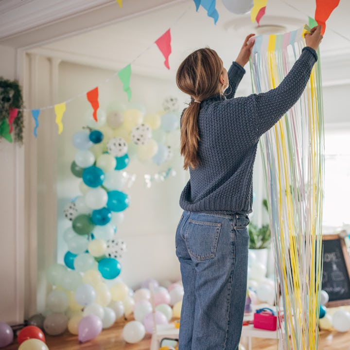 Young woman decorating room for birthday party