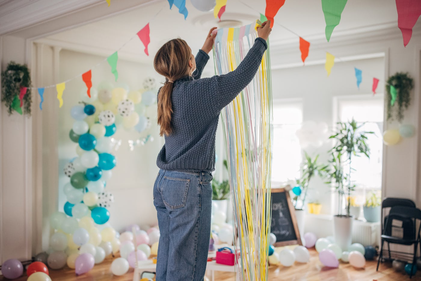 Young woman decorating room for birthday party