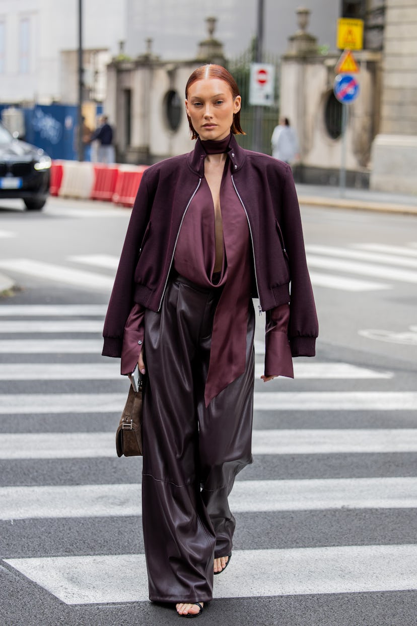 MILAN, ITALY - SEPTEMBER 18: Meredith Duxbury wears burgundy jacket, leather pants, top, brown bag o...