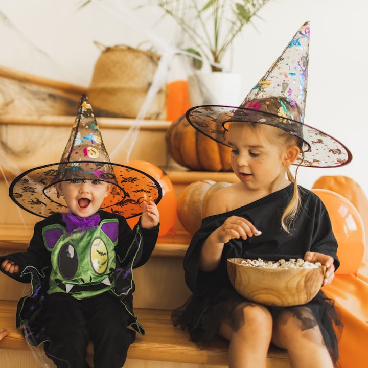 Mischief children laughing and fooling at home on Halloween celebration. House decorated with cobweb...