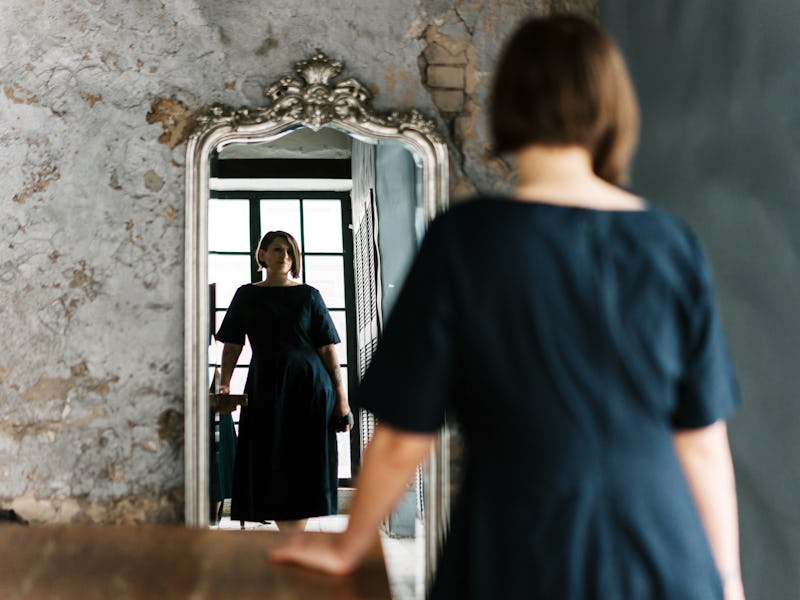 Reflection of a woman's face in mirror pieces on a wooden wall. Portrait of an emancipated businessw...