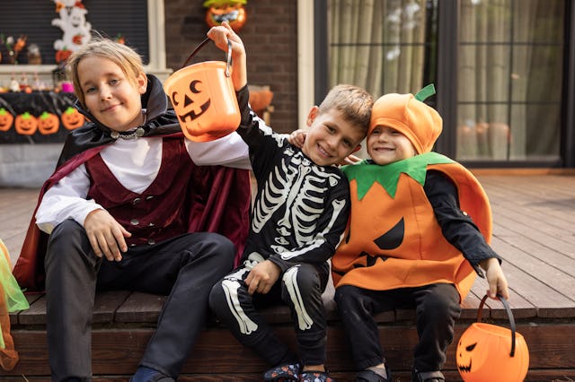 Kids sitting on the porch, preparing for Halloween. Spider-Man, ghost, and princess are among the mo...