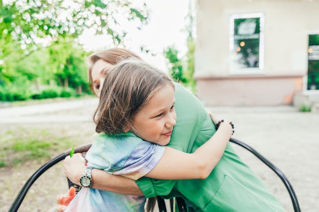 Pre-teen daughter lovingly hugs her mother in sidewalk cafe