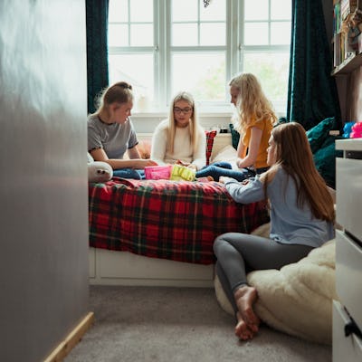 A small group of teenage girls playing with makeup on their bed.