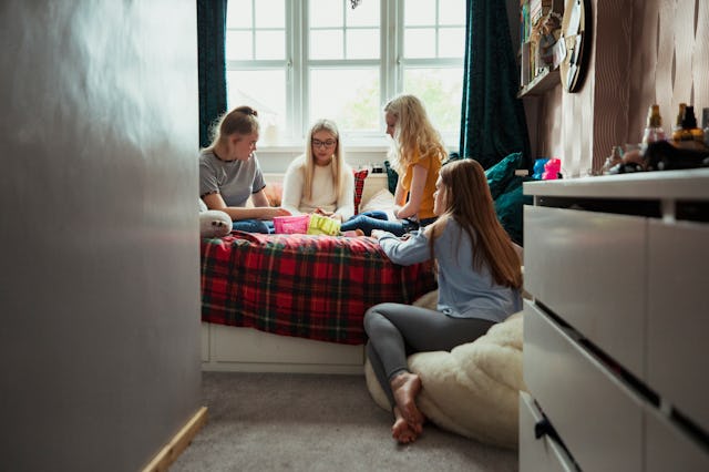 A small group of teenage girls playing with makeup on their bed.