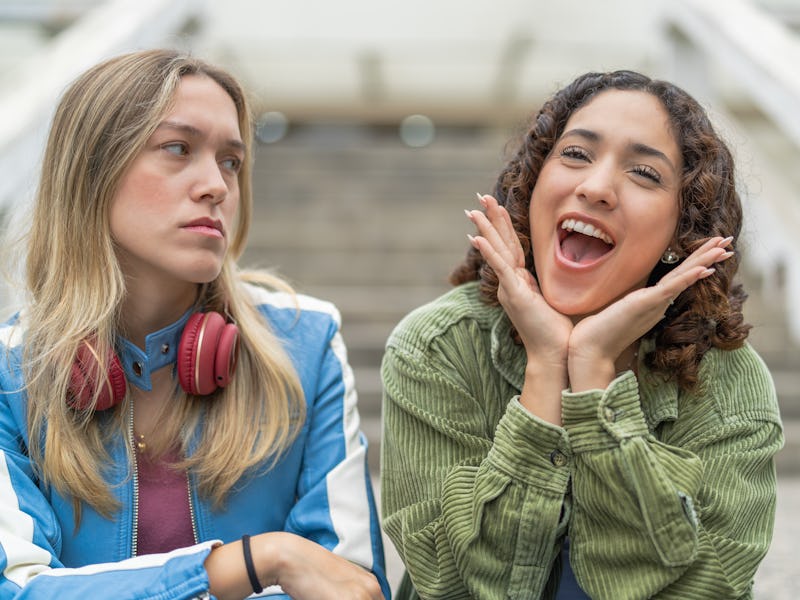 Girlfriends making happy and annoyed faces in the street, wearing jackets