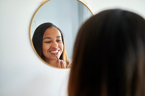 Woman putting lipstick in the mirror