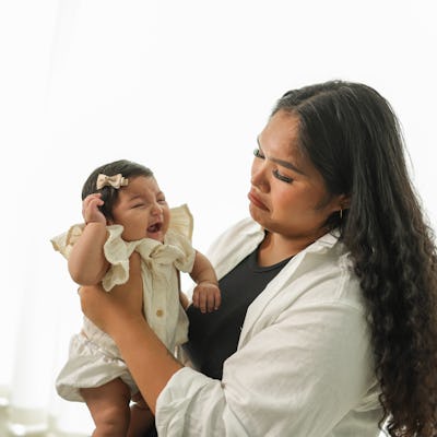 Portrait of a young mother holding her new born baby girl.
