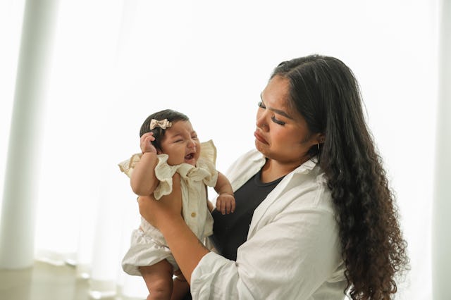 Portrait of a young mother holding her new born baby girl.