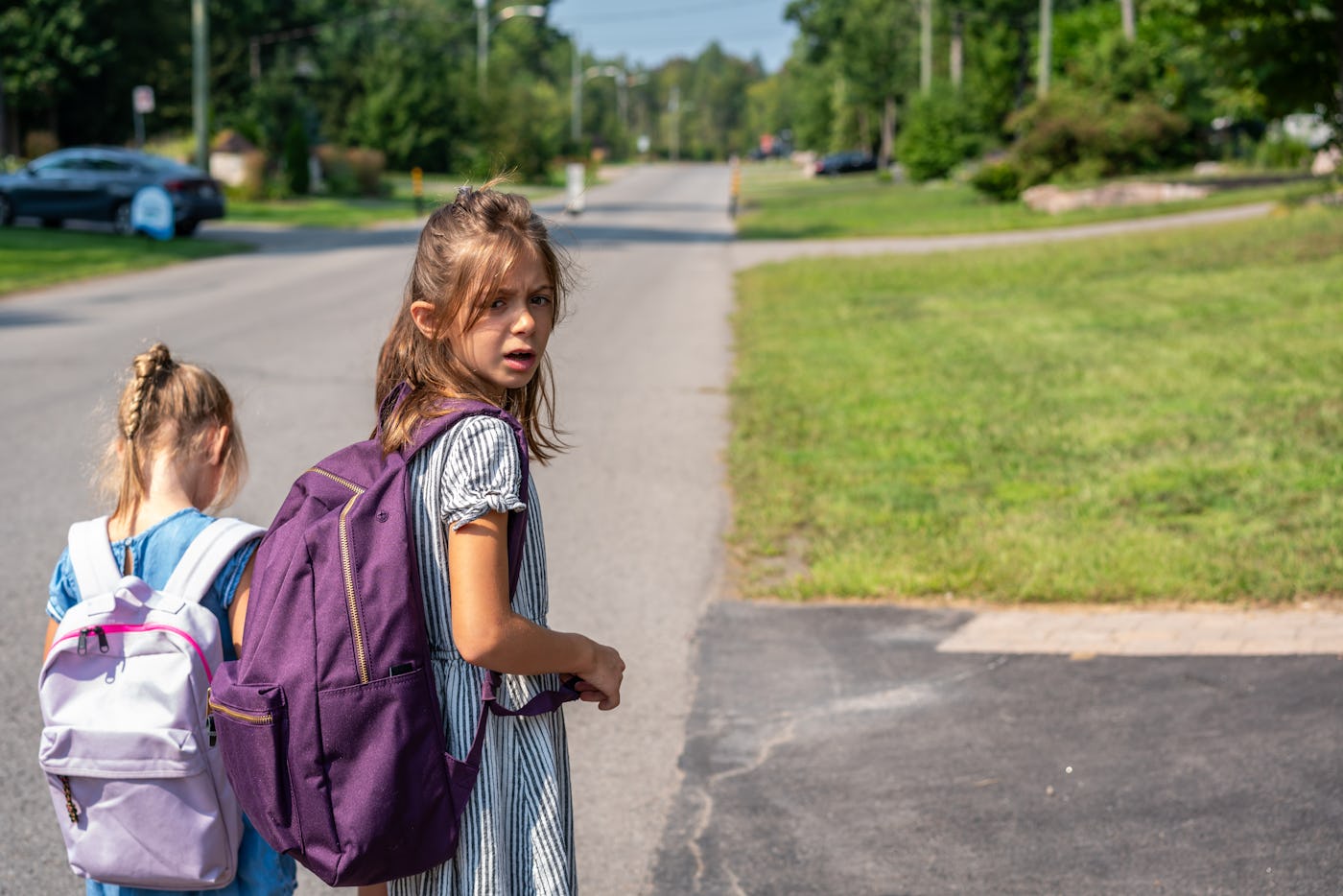 Two sisters waiting for the school bus in a sunny morning of summer.