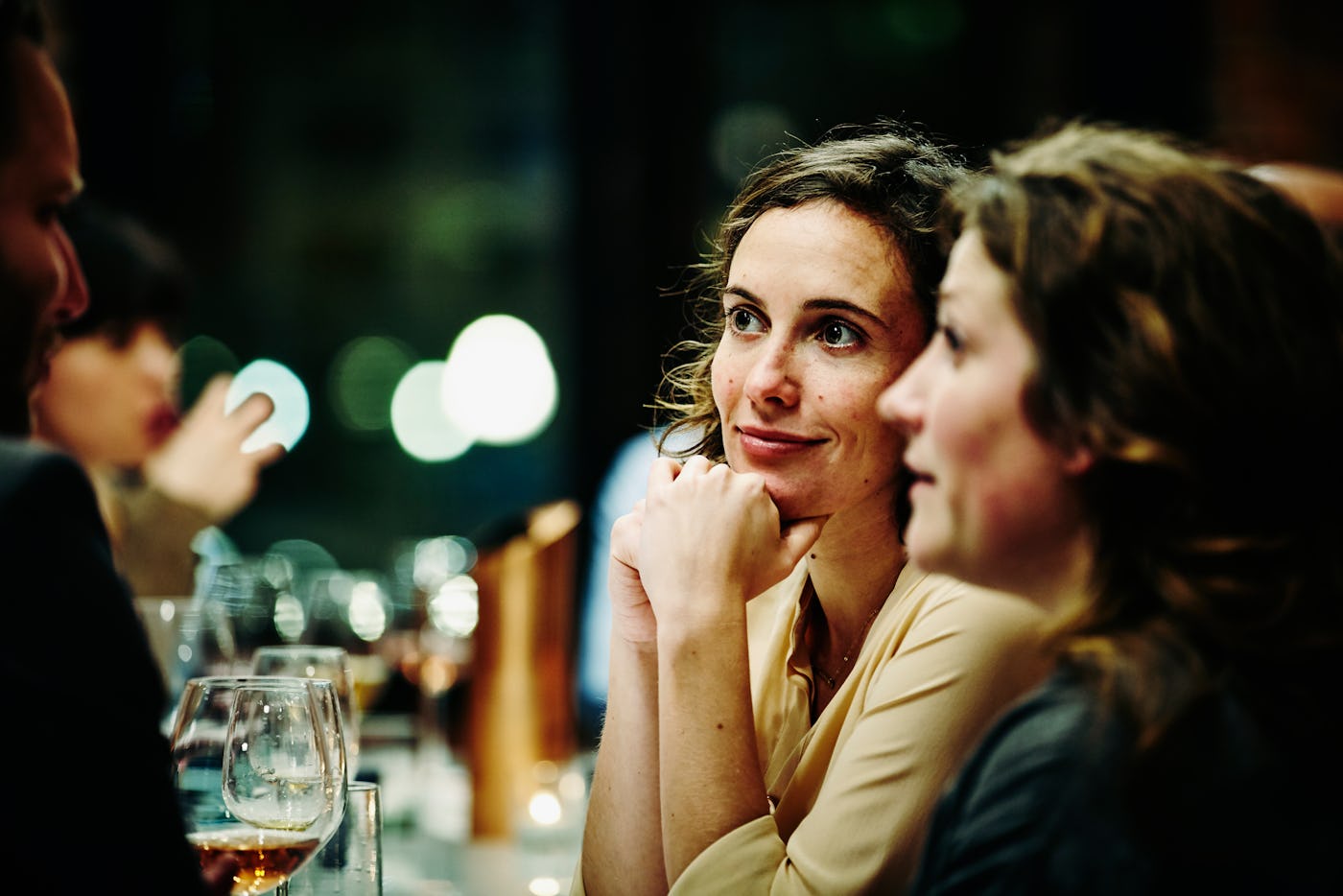 Smiling woman in conversation with friends during dinner party