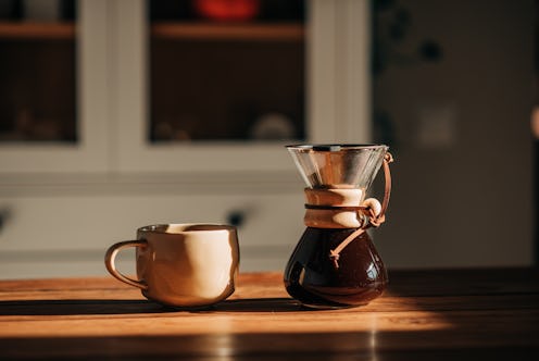 A hand pouring steaming coffee in to a cup on a work desk when work from home