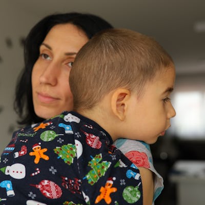 Caring mother carrying and embracing her tired and sleepy toddler boy