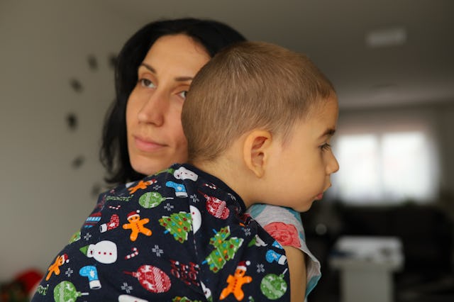 Caring mother carrying and embracing her tired and sleepy toddler boy