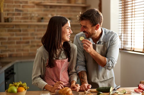 Happy couple talking and having fun while preparing healthy salad in the kitchen.