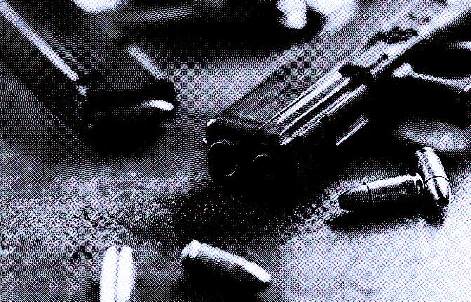 Close-up of a black metal 9mm automatic pistol with bullets all placed on a concrete table