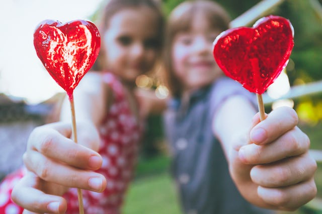 Two children with lollipops in heart shape having fun. Love concept. Valentine's day.