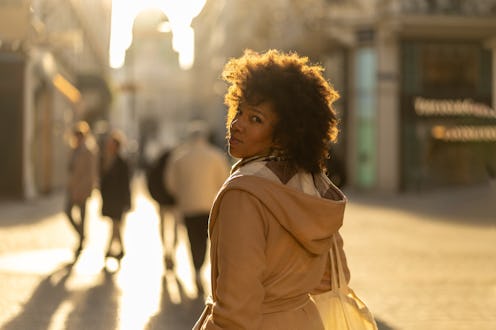 Portrait of a beautiful mixed race woman looking at camera over shoulder and smiling during sunset i...