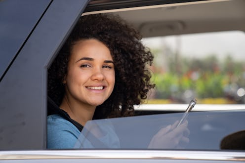 Beautiful woman in a crowdsourced taxi using her phone and smiling while sitting in the back seat