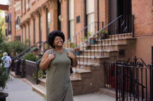 Happy African American female student enjoying while walking on the street.