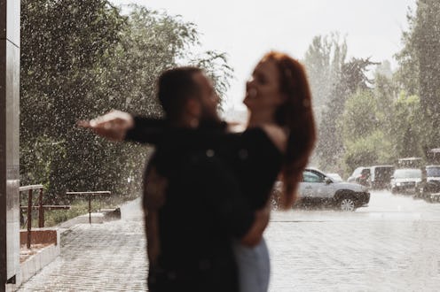 Photo of muscular man in black t-shirt holding beautiful redhead lady in arms, spinning around, maki...