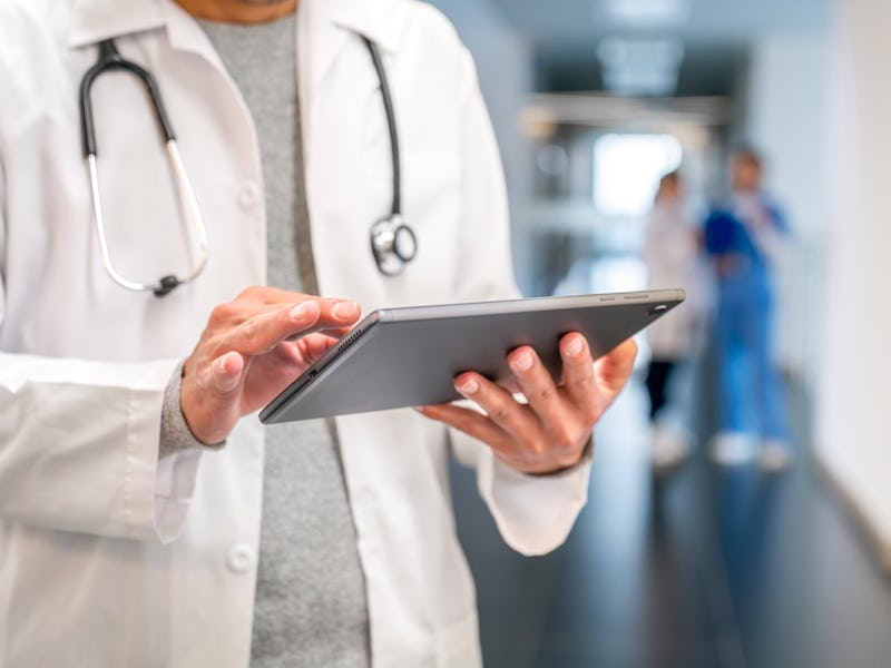 Close-up on a doctor using a digital tablet at the hospital to check a medical record - healthcare a...