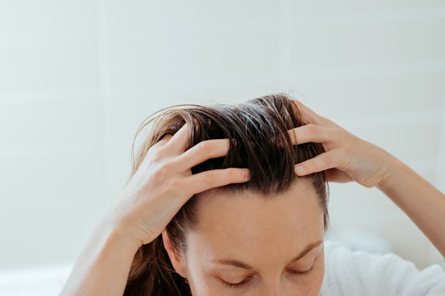 Woman delicately doing massage of her scalp with cosmetic oil