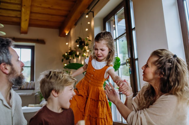 Real family, little girl crying is upset during family game night. Sore loser, girl is annoyed whet ...