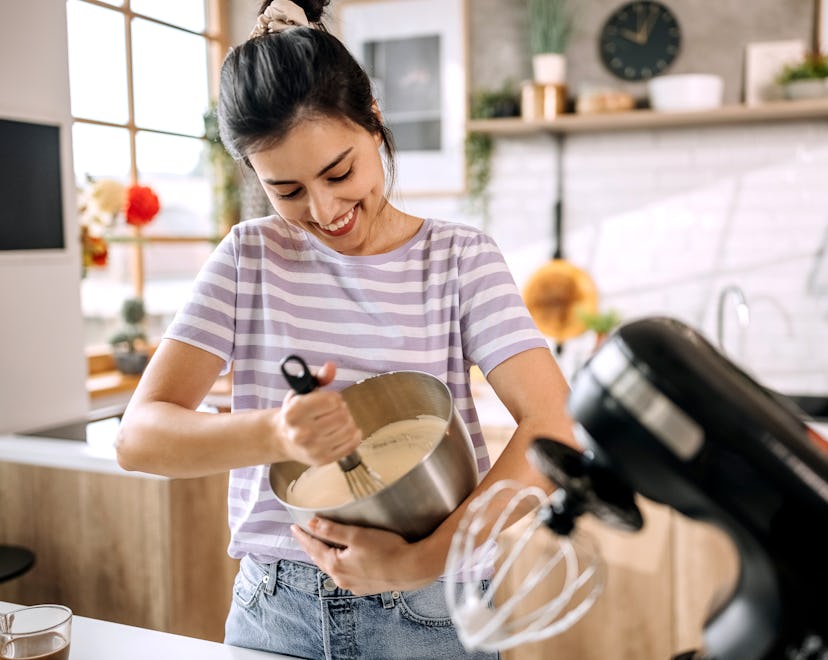 Young beautiful woman mixing cake mixture in her domestic kitchen