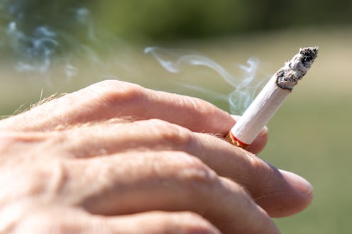 Human hand holds cigarette in the nature