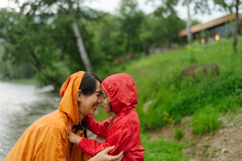 Photo of a mother and daughter enjoying a rainy day outdoors, exchanging smiles, glances, and kisses...