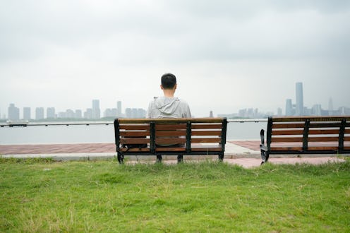 The man was resting on a bench by the river